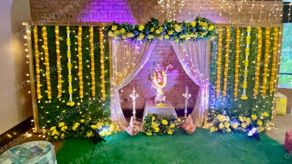 Marigold strings and greenery around a lit shrine for a haldi ceremony